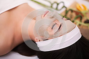 Spa. Beautiful young woman is getting facial clay mask at spa, l