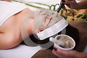 Spa. Beautiful young woman is getting facial clay mask at spa, l