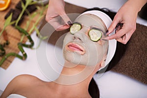 Spa. Beautiful young woman is getting facial clay mask at spa, l