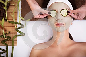 Spa. Beautiful young woman is getting facial clay mask at spa, l