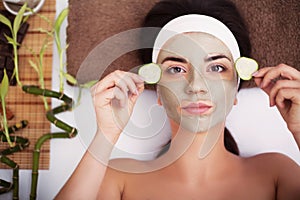 Spa. Beautiful young woman is getting facial clay mask at spa, l