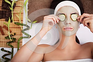 Spa. Beautiful young woman is getting facial clay mask at spa, l