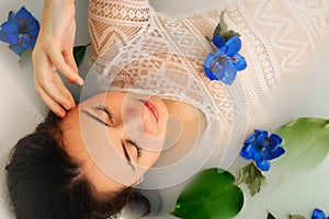 Spa beauty model girl taking milk bath, spa and skin care concept. Beauty young Woman with bright makeup and blue rose