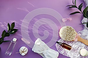 SPA beauty treatment with hygiene accessories, natural soap, essence oil, massage brush, bath bomb, sponges on purple
