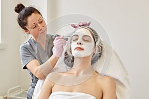 Spa beauty treatment, skincare concept. Woman getting facial care by beautician at spa salon, cosmetologist applays face peeling