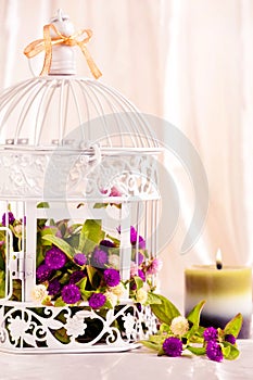 Spa candle and flowers in decorative cage.