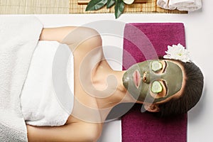 Spa Clay Mask. Beauty Woman with clay facial mask  and cucumbers on eye