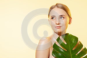 Spa. Close up of beautiful female face with green leaves over white background. Cosmetics and makeup, natural and eco