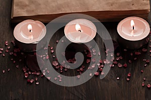 Spa composition with aroma candles and empty vintage open book on wooden background. Treatment, aromatherapy