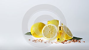 SPA composition. A bottle of face serum with natural lemon essential oil  together with a group of lemons on a light background