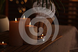 Spa composition with burning candles on massage table in wellness canter, space for text