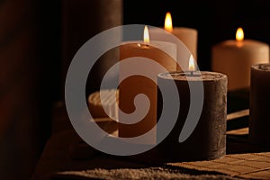 Spa composition with burning candles on massage table in wellness canter, space for text