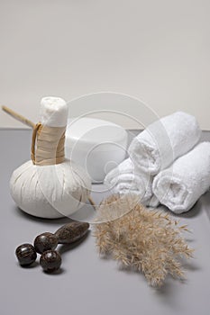 Spa composition of herbal massage bags, a jar of oil and a hand-held wooden massager