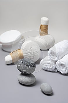 Spa composition of herbal massage bags, a jar of salts, towels and stones.