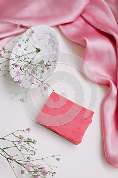 Spa composition with pink soap bar with ceramic soap dish, silk babric and flowers
