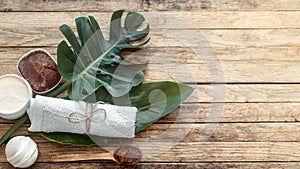 Spa composition with towels and tropical leaf on a wooden background