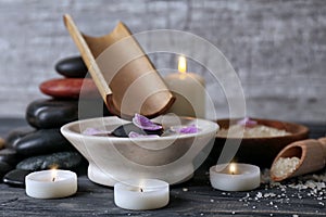 Spa composition with water in bowl and candles on table