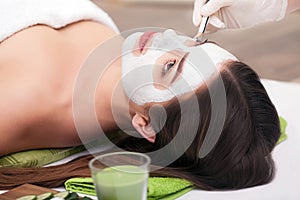 Spa concept. Hand applying nourishing mask on female face in spa salon