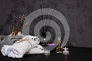 Spa concept. Lavender salt for a relaxing bath, aroma oil, candles, white towels, dry lavender flowers, perfume on a gray