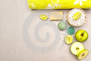 Spa concept, natural ingredients. Bath towel, sea salt with lime, apple, olive and mint soap, sponge. On a stone background, top