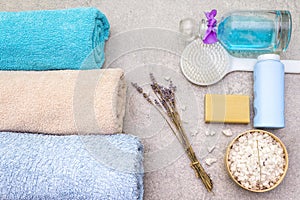 Spa concept, natural ingredients. Bath towels, sea salt with lavender, natural olive soap, shower gel and brush. On a stone