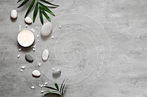 Spa concept on stone background, palm leaves, candle and zen, grey stones, top view