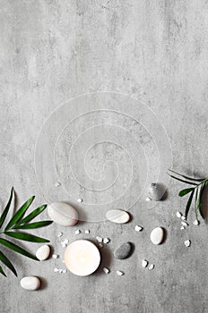 Spa concept on stone background, palm leaves, candle and zen, grey stones, top view