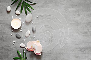 Spa concept on stone background, palm leaves, flower, candle and zen, grey stones, top view, copy space