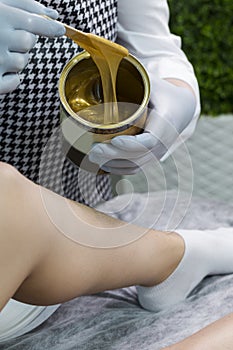 Spa Concepts. Close-up of Beautician Preparing for Wax Depilation of Woman Legs By Applying Liquid Wax With Spatula on Female Legs