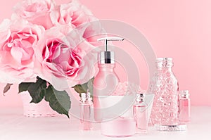 Spa cosmetics products, roses in pastel pink and silver color - cream, bath salt, essential oil, soap, bottle, bowl, towel.