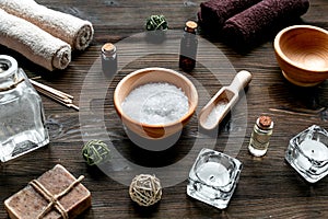 Spa cosmetics with soap, salt, oil, towels, candles on wooden background