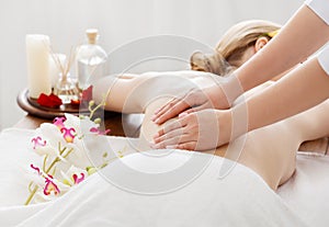 Spa day. Girl receives massage on table with flowers and oil