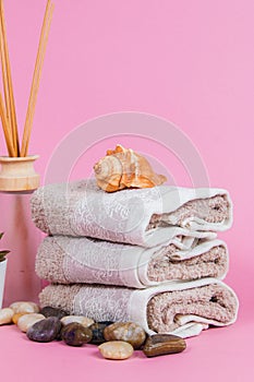 Spa essentials, aroma sticks stones, towels and a plant on a pink background  Keywords language: English