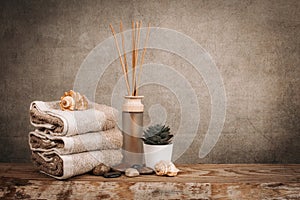 Spa essentials, aroma sticks, stones, towels, sea shell on a wooden rustic background