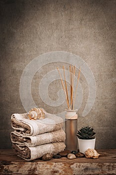 Spa essentials, aroma sticks, stones, towels, sea shell on a wooden rustic background