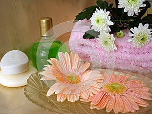 Spa essentials (soap, bottle of shampoo and towel with flowers)