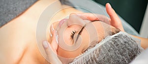 Spa facial skincare. Close-up of a young caucasian woman getting spa moisturizing face massage treatment at beauty spa