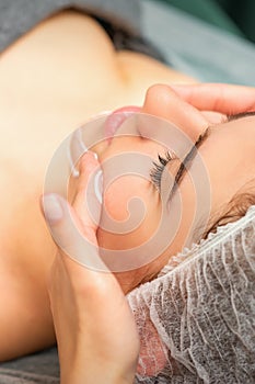 Spa facial skincare. Close-up of a young caucasian woman getting spa moisturizing face massage treatment at beauty spa