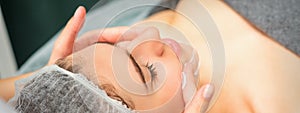 Spa facial skincare. Close-up of a young caucasian woman getting spa moisturizing face massage treatment at beauty spa