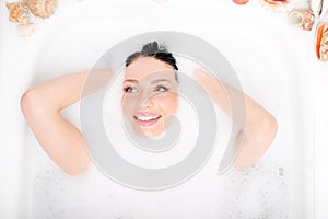 Spa fun: beautiful blue eyes brunette girl attractive young woman relaxing plunged into the foam and happy smiling portrait