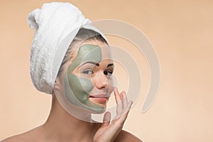 Spa girl with a towel on her head applying facial