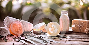 Spa handmade soap with white towels and sea salt, the composition of the tropical leaves with a candle, wooden background