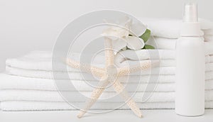 Spa and health care concepts setup with stack of white towels star fish,Gardenia flowers and sprat bottle on white background