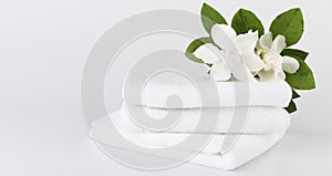 Spa and health care concepts setup with stack of white towels  and tropical Gardenia flowers on white background