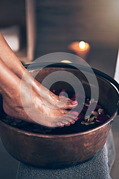 Spa, health and woman feet in water to soak with flowers for a luxury, glamour and pedicure treatment. Wellness, beauty