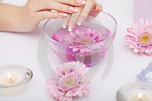 Spa Manicure. Woman Hands With Perfect Natural Healthy Nails Soaking In Aroma Hand Bath. Closeup Of Glass Bowl With Water And Blu