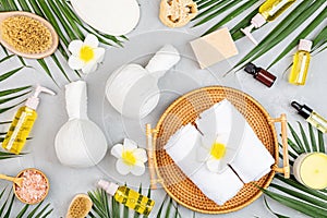 Spa massage Aromatherapy body care background. Spa herbal balls, cosmetics, towel and tropical leaves on gray concrete table. Top