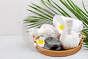 Spa massage Aromatherapy body care background. Spa herbal bags, towel and tropical flowers on gray concrete table. copy