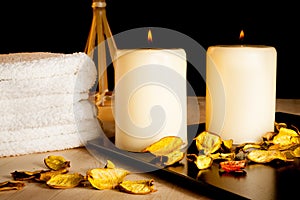 Spa massage border background with towel stacked, perfumed leaves and candles