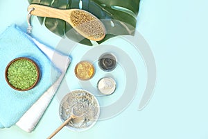 Spa massage clay powder, face masks, bath salt, towel, shea butter on blue table background.